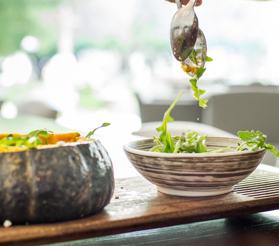Salad being tossed with silver spoons