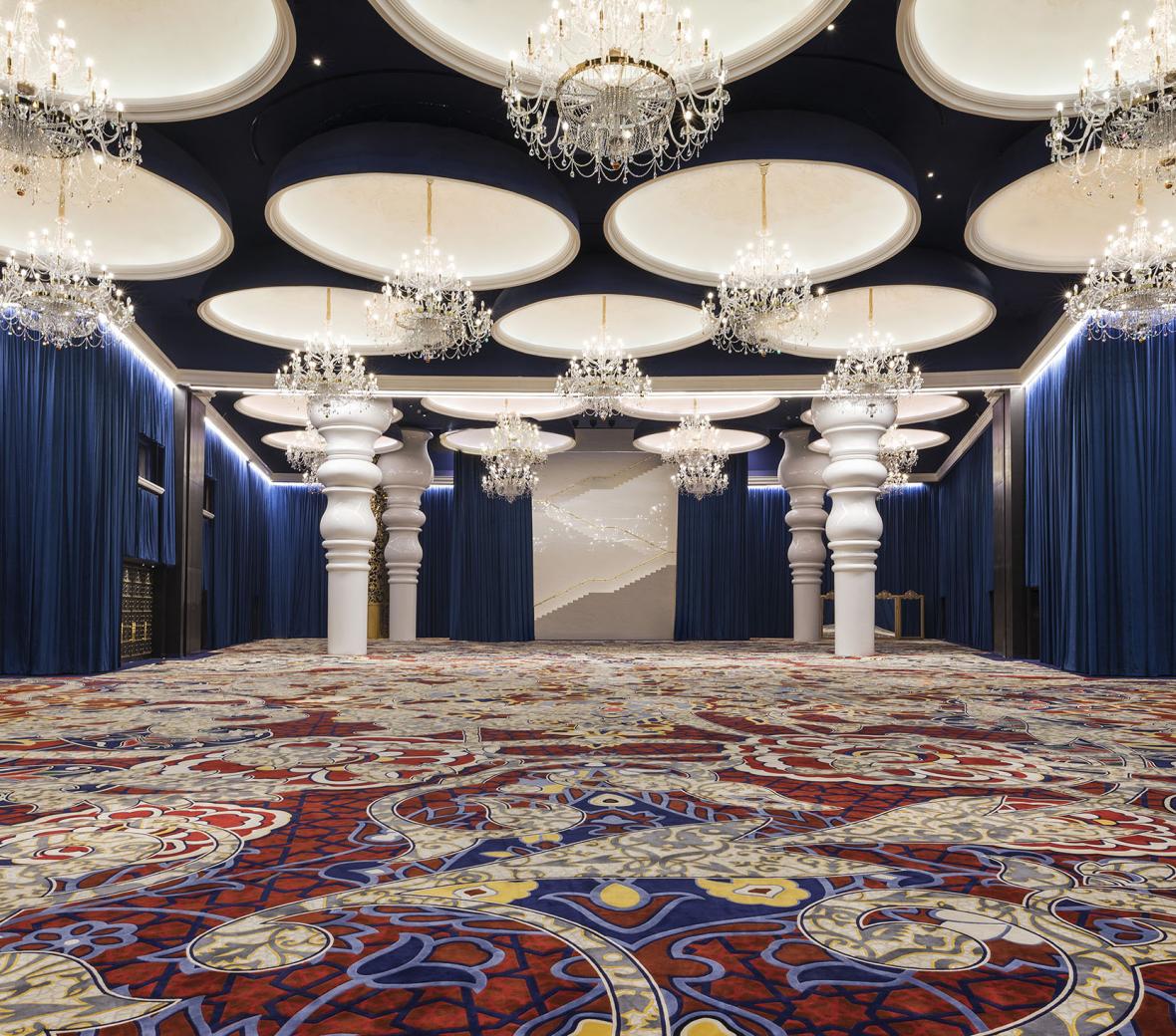 Grand ballroom with chandeliers above an ornate carpet