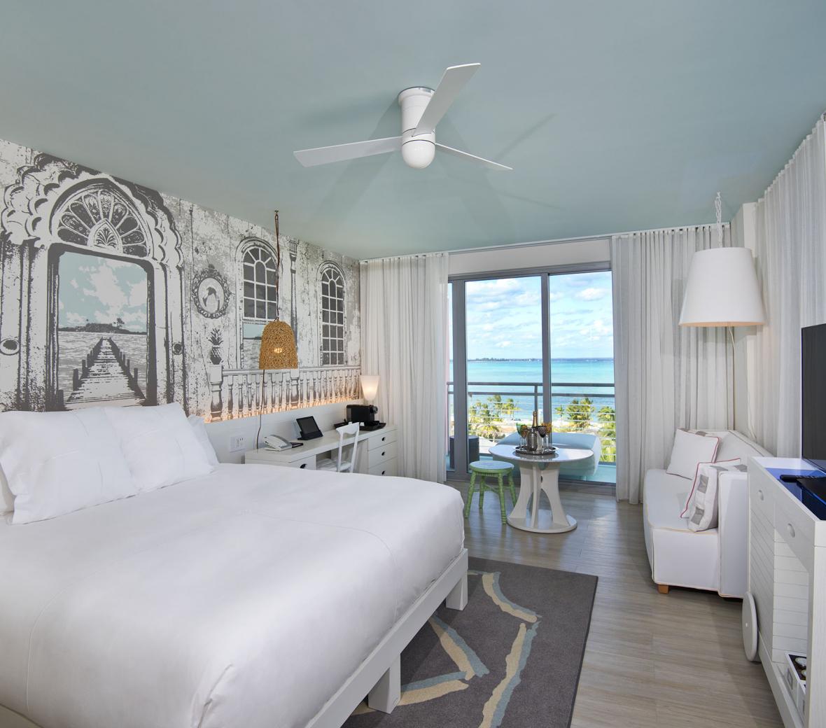 A hotel bedroom with a patio window showing the ocean.