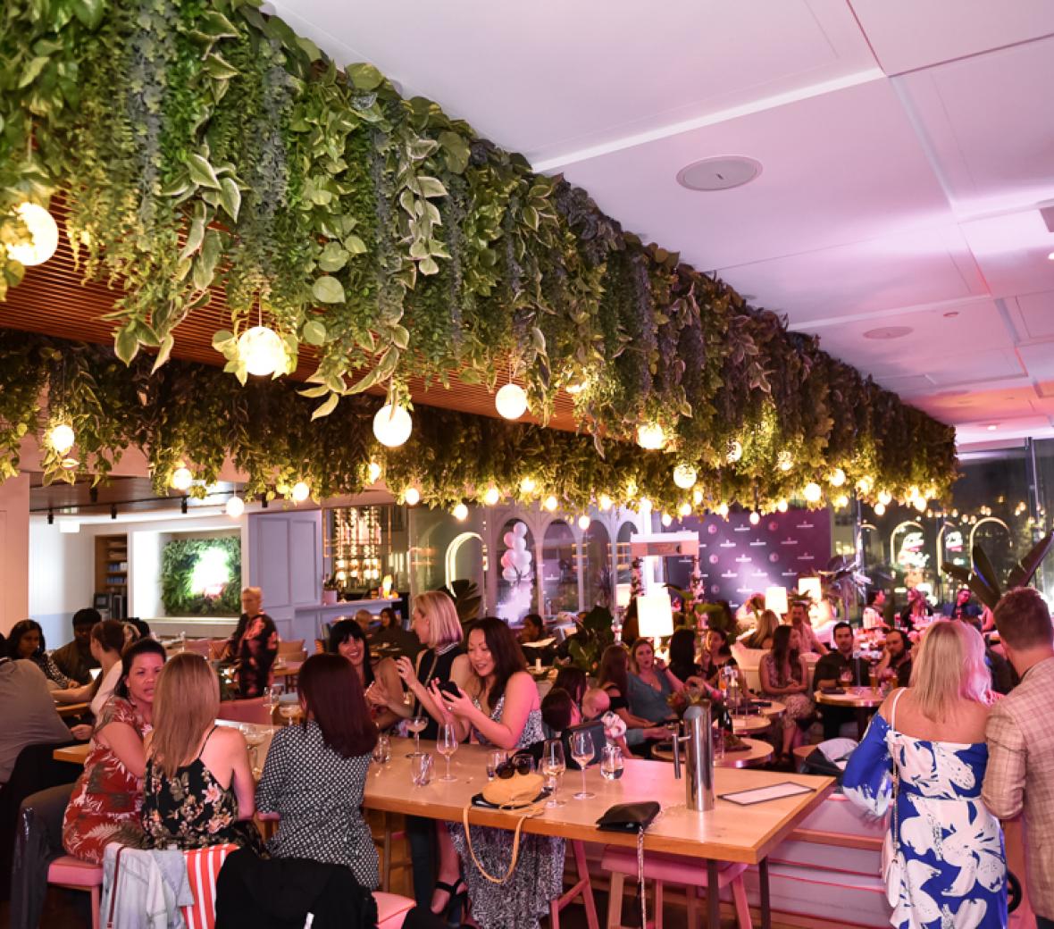 An image of people enjoying cocktails at a bar with atmospheric lighting.