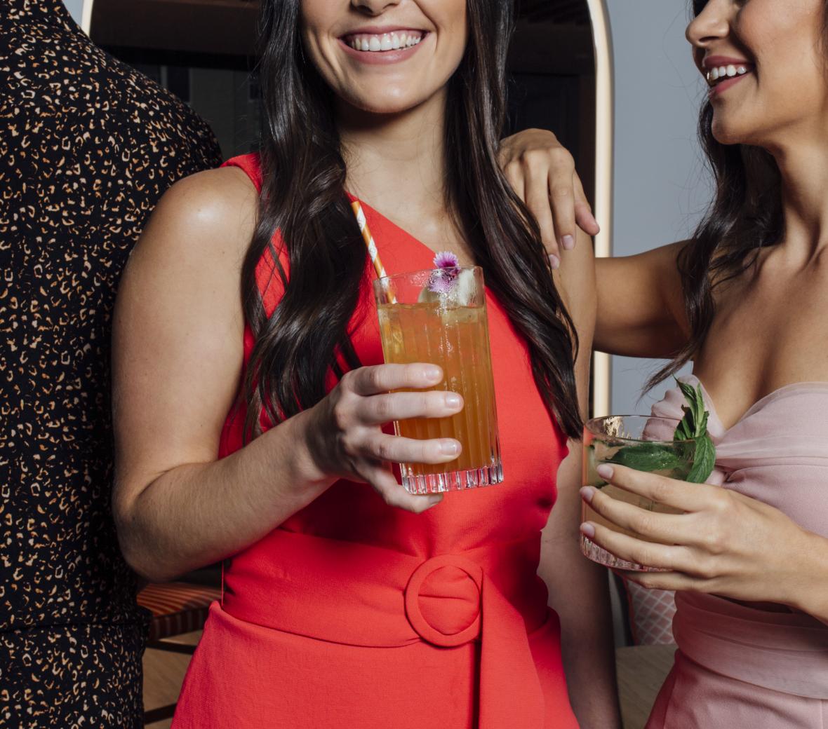 Photo of two women smiling and holding cocktails.