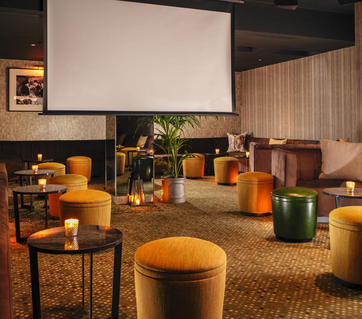 plush stools surround a large projection screen for watching movies