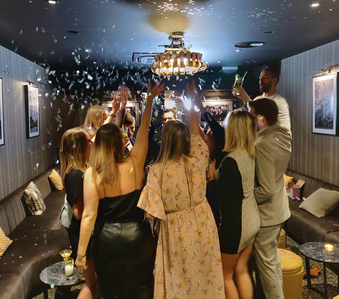 group of people in a bar all raising a glass in cheers