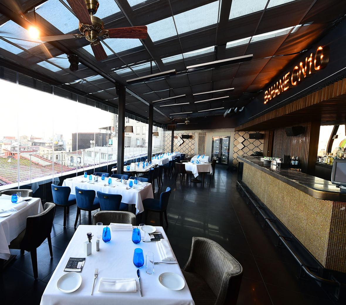 A restaurant dining room with a cityscape outside the window.