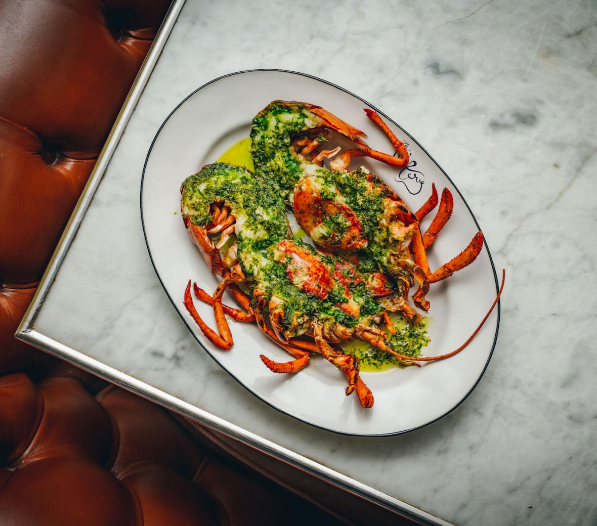 plate with whole lobster cut in two and green sauce