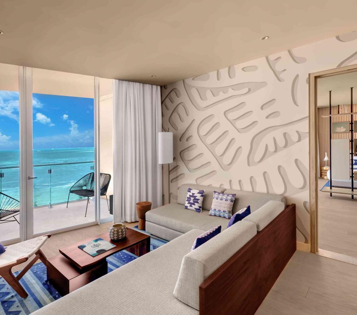 View of living room with an open door leading to the deluxe ocean front one bedroom king suite