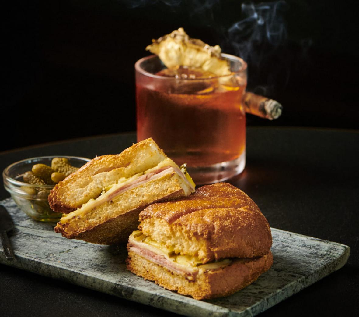 sandwich next to a drink and a cigar