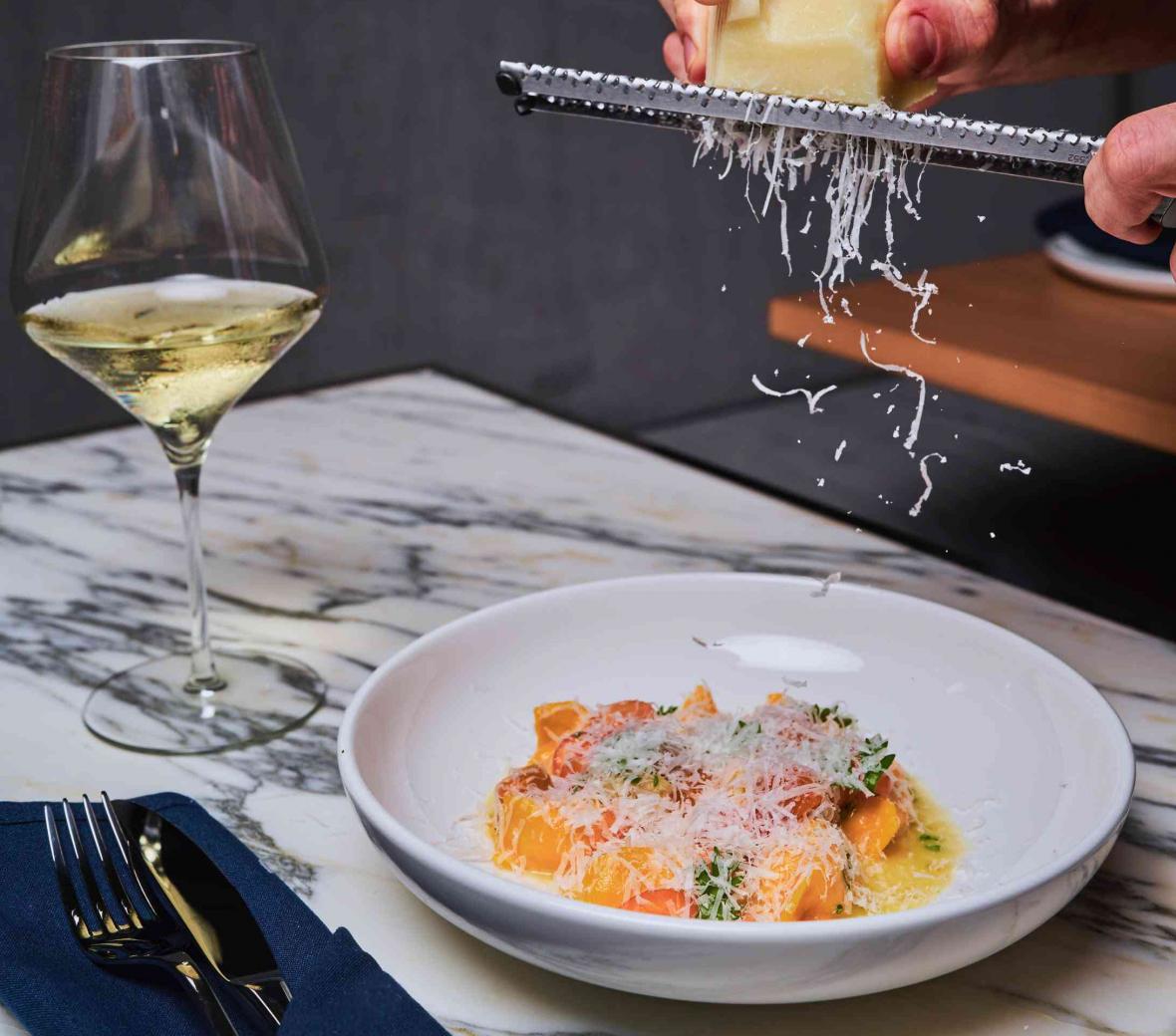 A man grating cheese over pasta