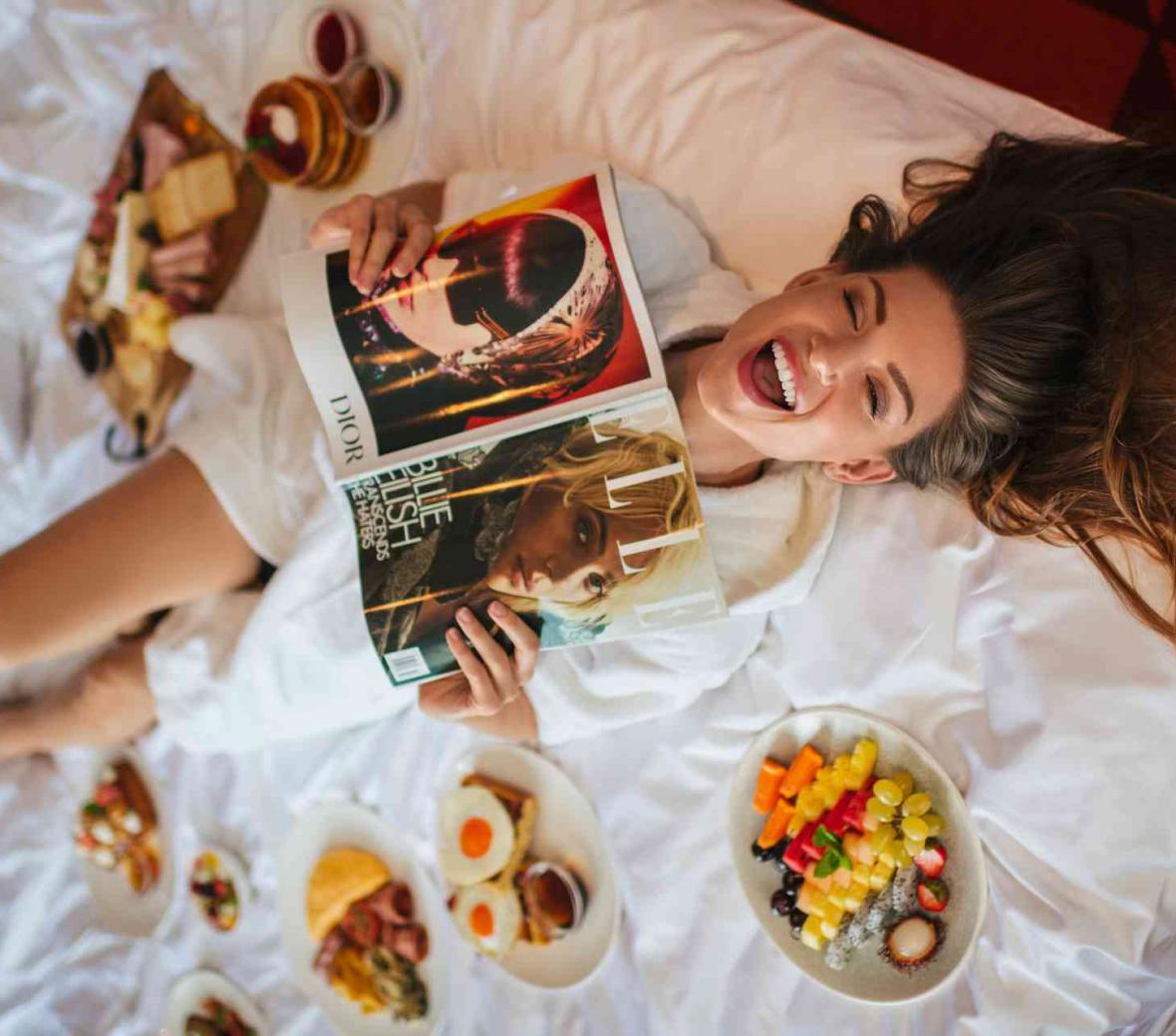 Lady reading a magazine and having breakfast in the hotel room