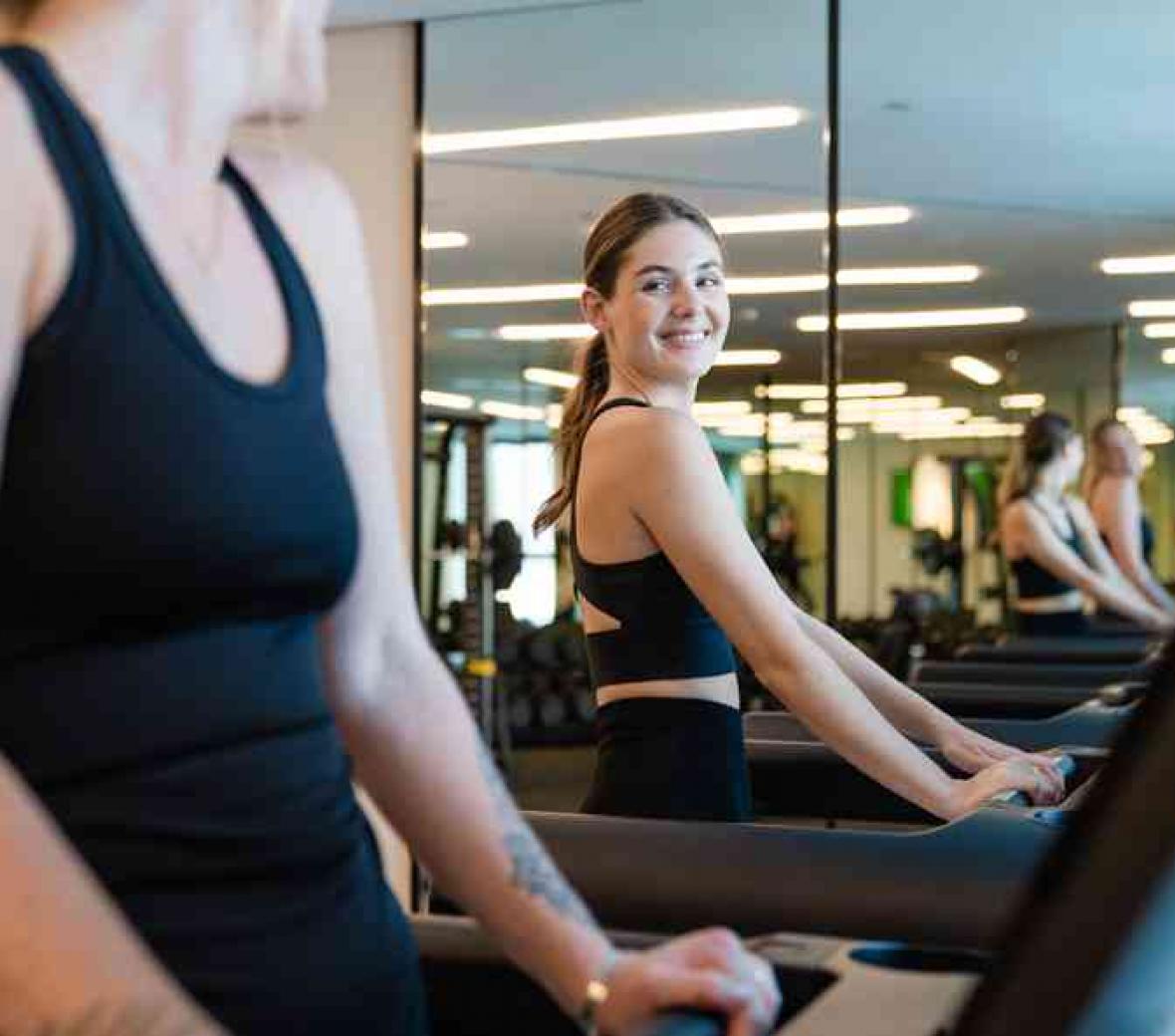 two ladies talking while walking on a treadmill