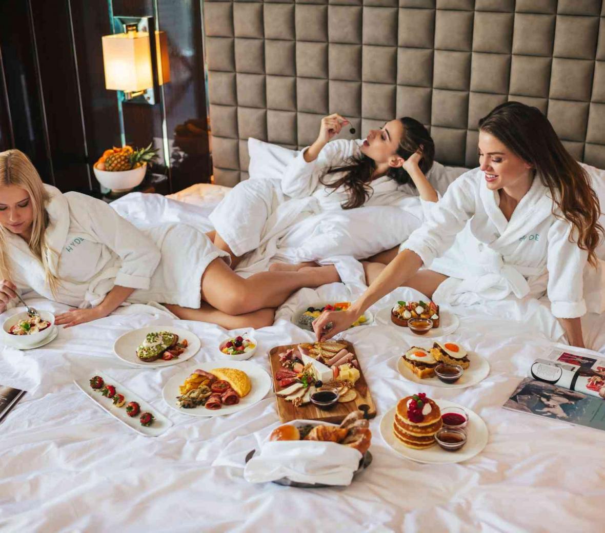 Women eating room service on a bed