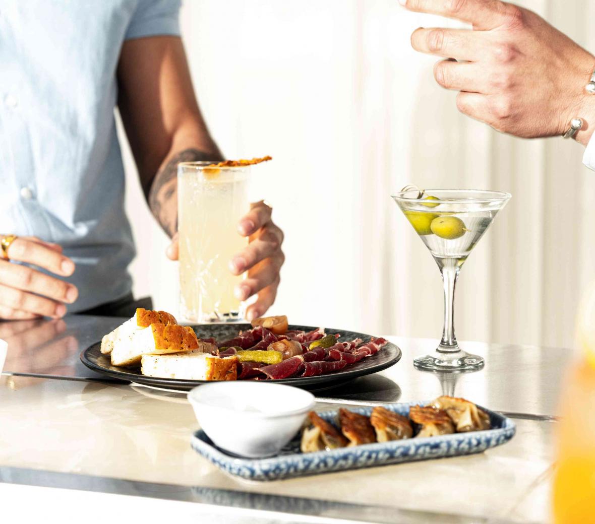 Two men enjoying cocktails and snacks