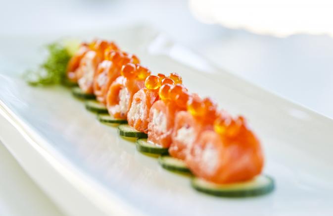 Salmon sushi topped with row on a bed of cucumber.