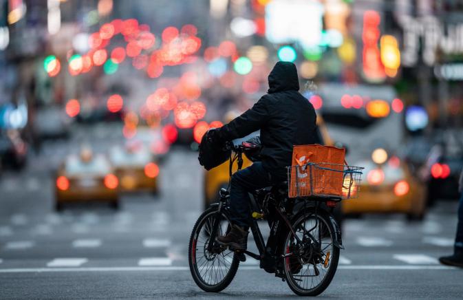 Delivery man with black jacket on a bike
