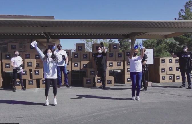 group of people in white tshirts handing out care package boxes