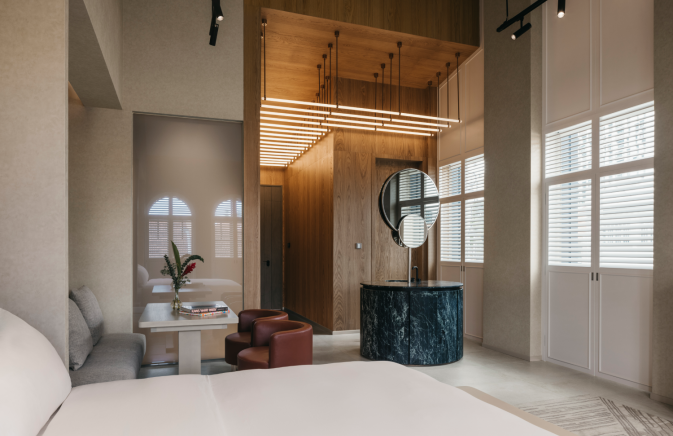 Mondrian Singapore contemporary hotel room featuring a bed, desk, mirror and socializing area