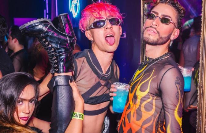 people posing for a photo in a club, holding a blue cocktail