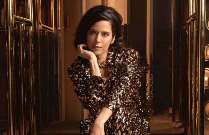 woman dressed up with elbow on knee and palm holding chin up