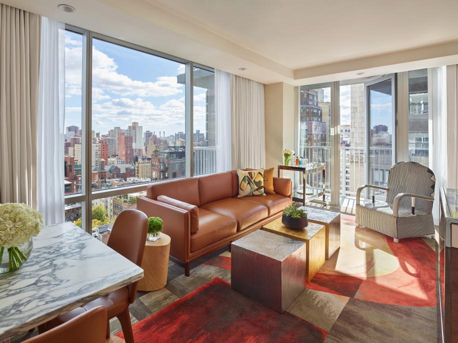 A bright hotel room suite with floor to ceiling windows