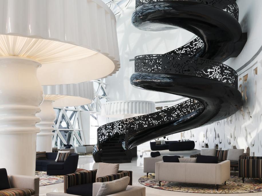 A brightly sit atrium with a black spiral staircase