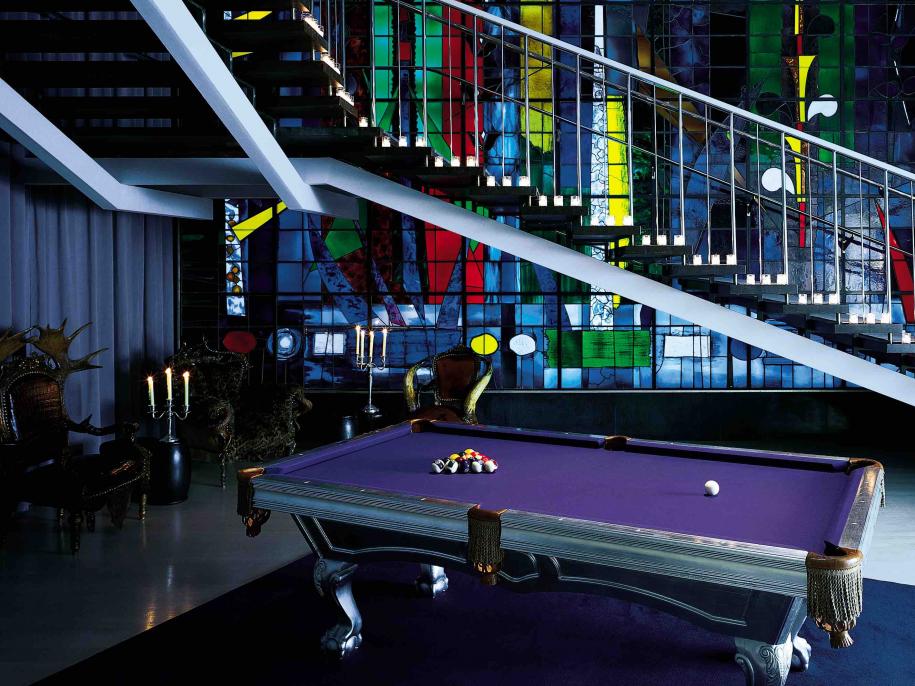 a purple pool table in front of colourful glass windows