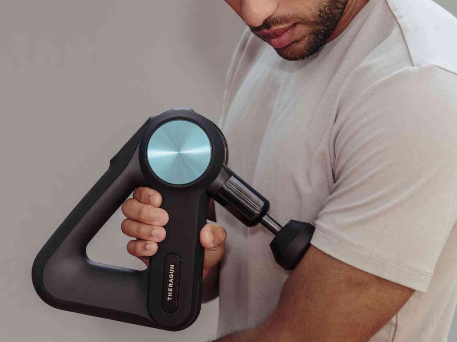 man using theragun pro on arm