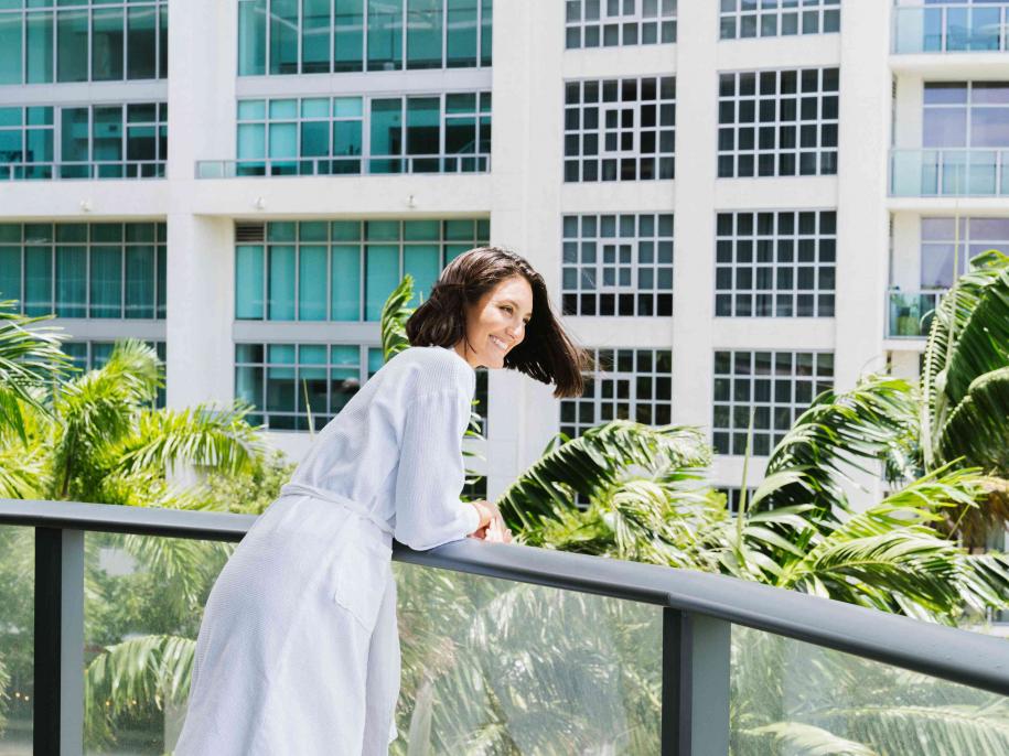 Woman in a white bathrobe looking over the hotel balcony. 