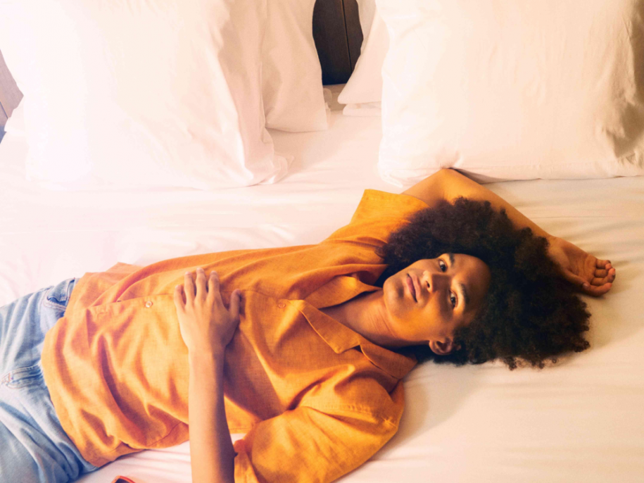 woman on bed with sunglasses beside her