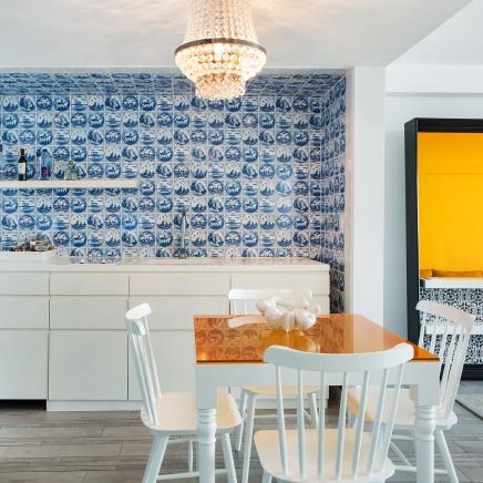 A table with chairs around it in a kitchenette with decorative wallpaper.