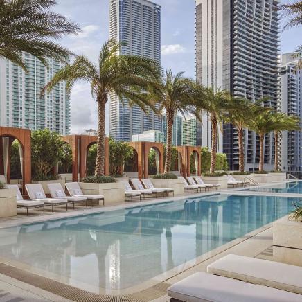 pool surrounded by white lounge chairs and palm trees