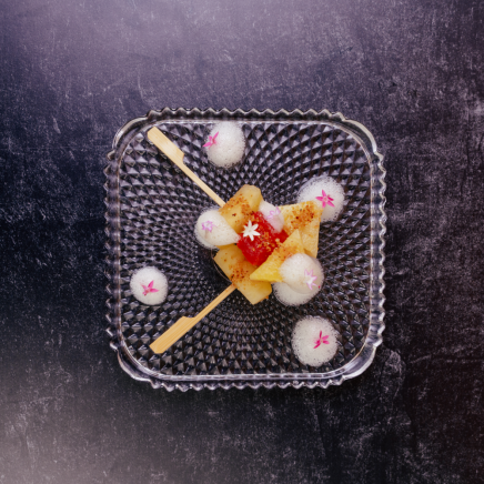 pineapple and watermelon on skewers on a clear glass plate with foam