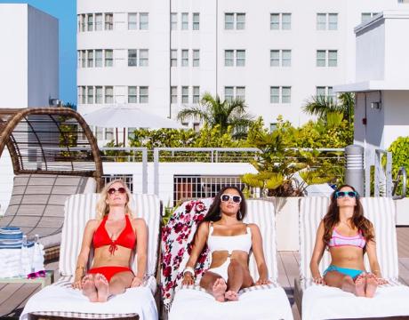 three women sunbathe outside by Redbury pool