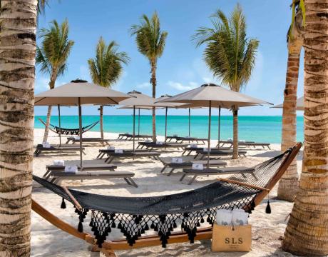 Sitting area on the beach with hammocks and umbrella covered chaise loungers