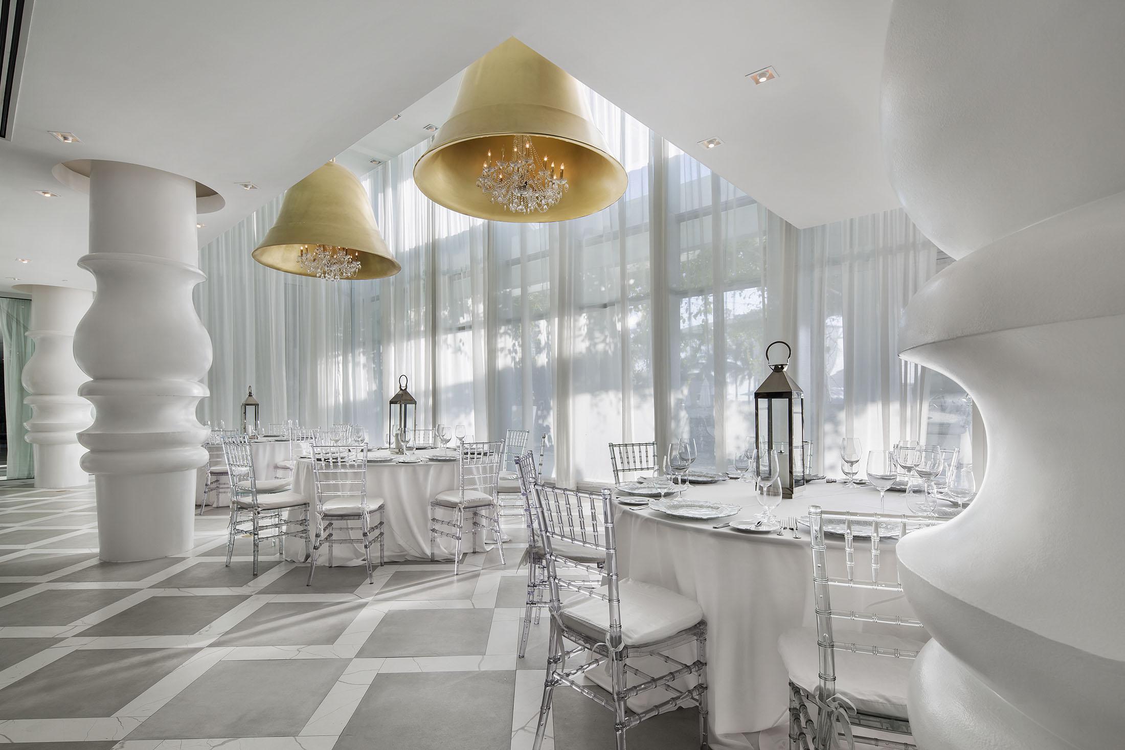 Tables and chairs set up for an event in a white room.
