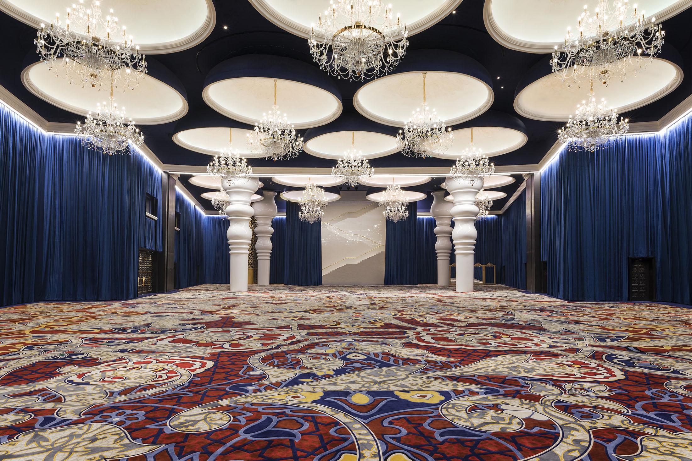 Grand ballroom with chandeliers above an ornate carpet