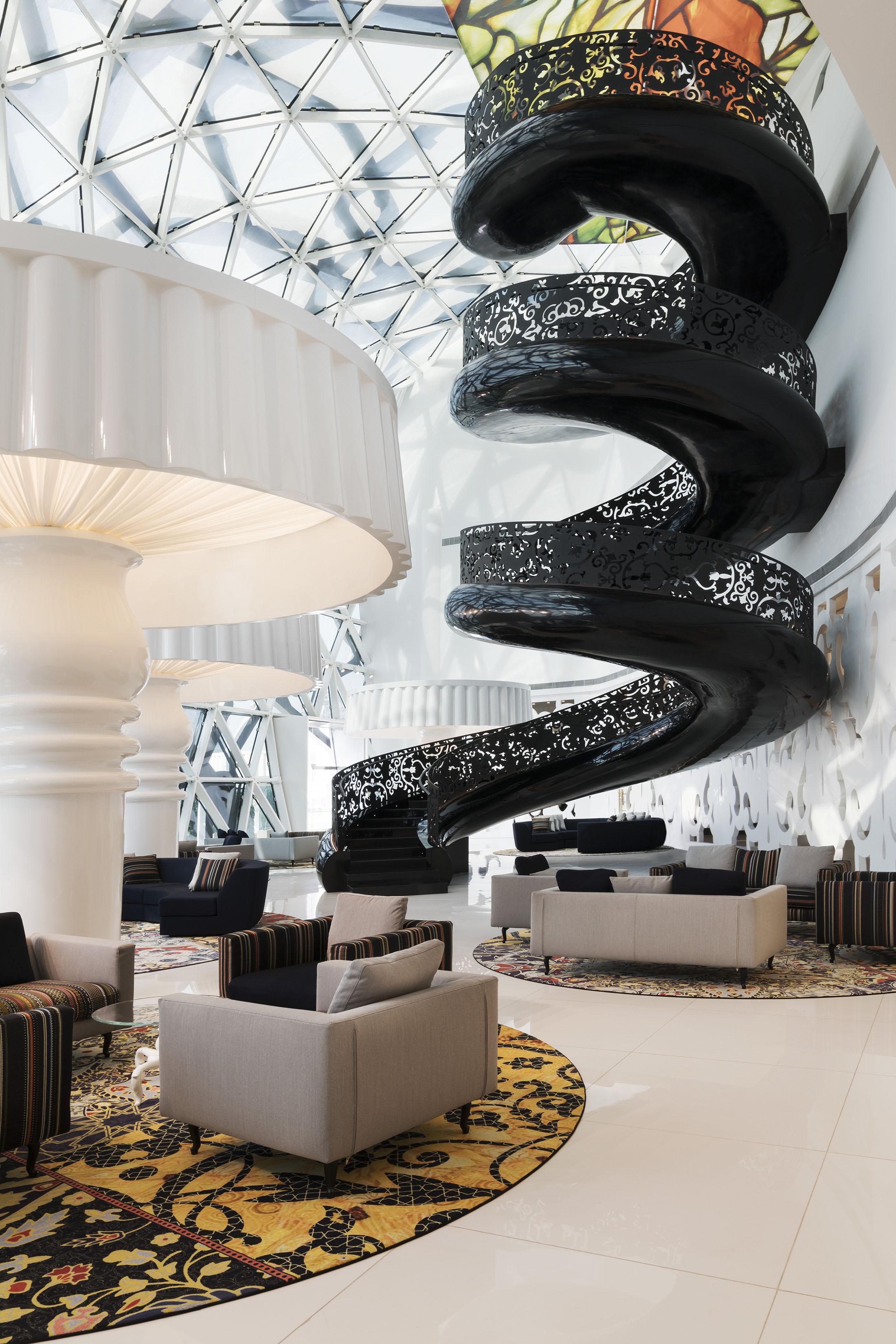 A brightly sit atrium with a black spiral staircase