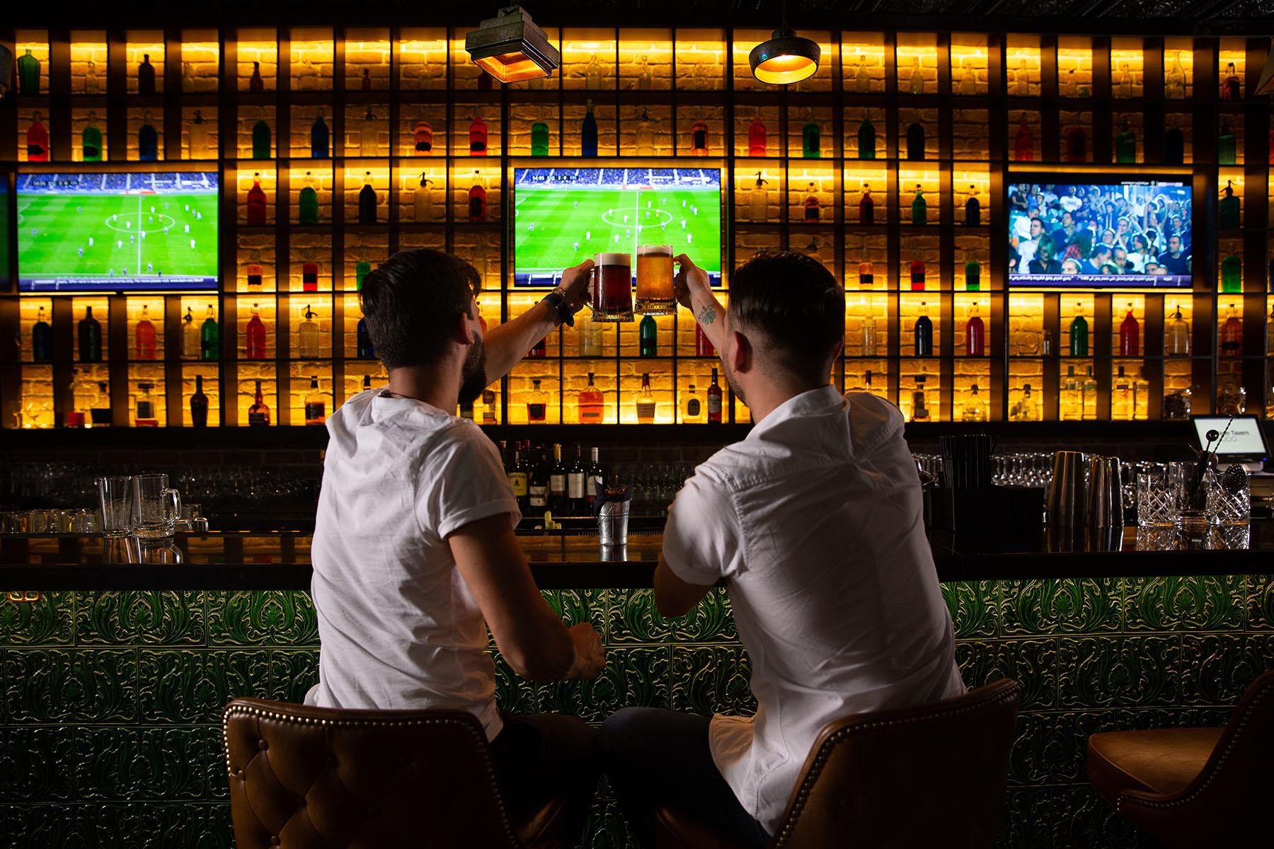 Men cheers at bar with soccer game on in background