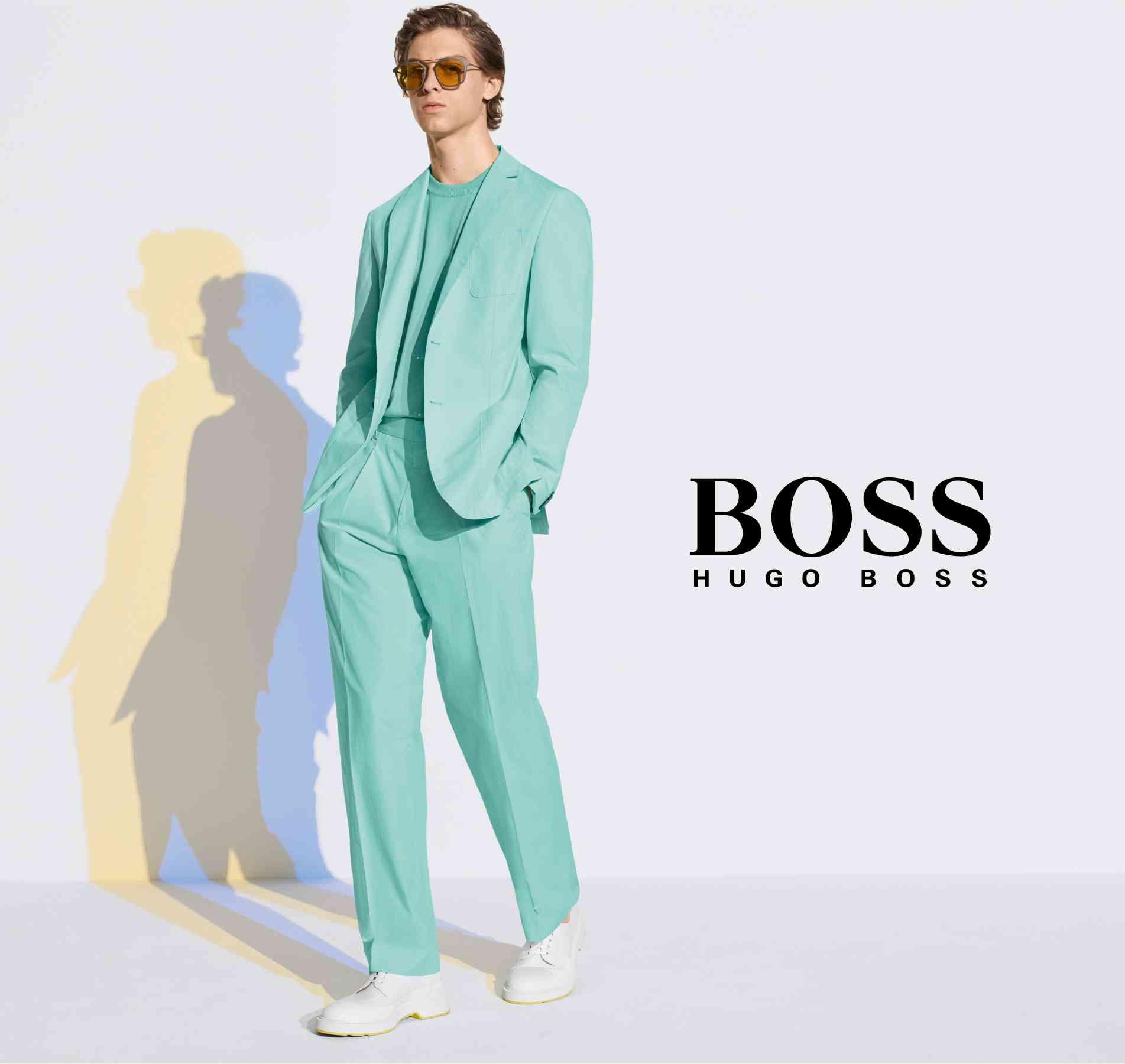 man in green suit next to hugo boss logo