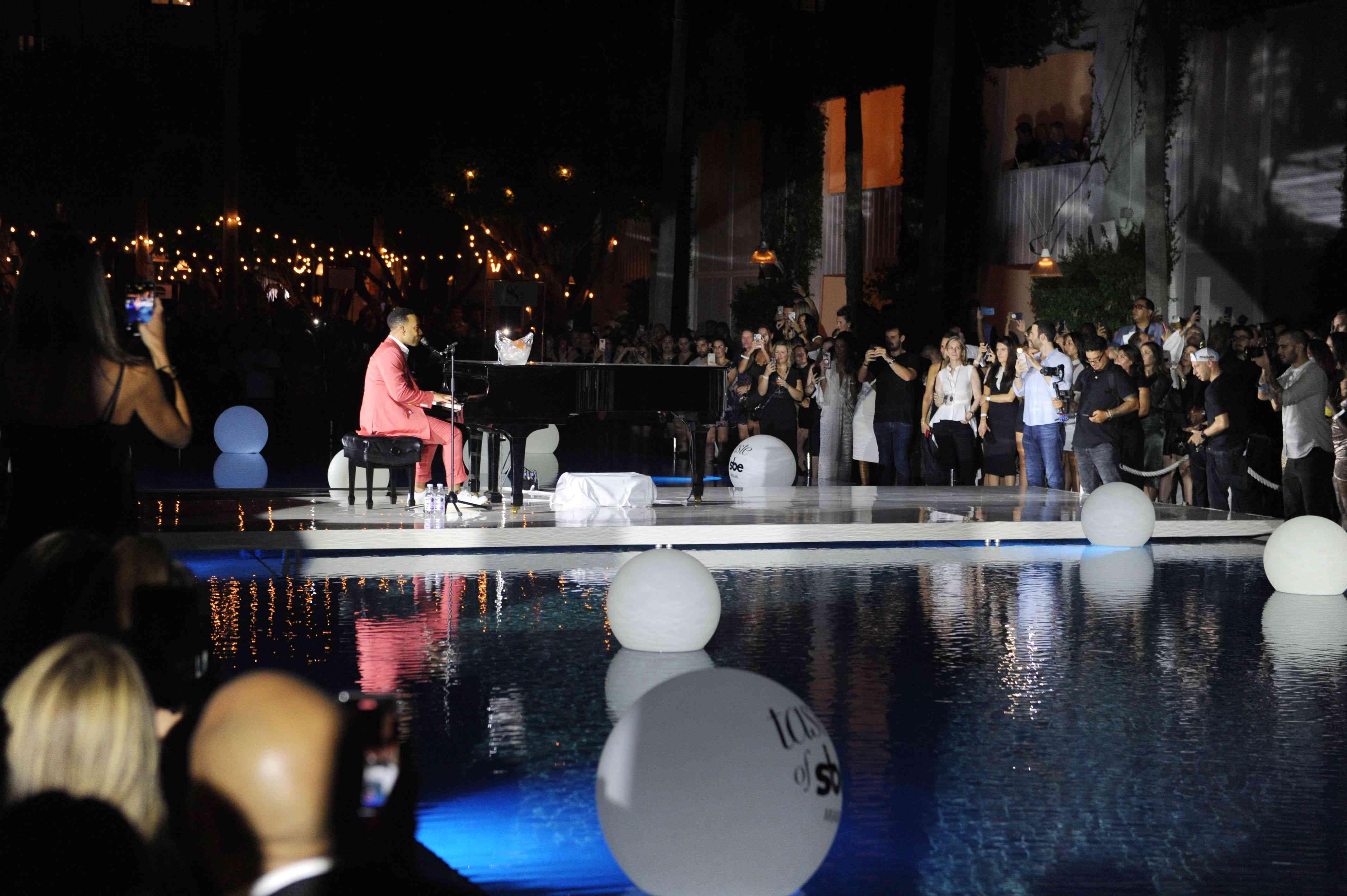 John Legend at a piano by a pool