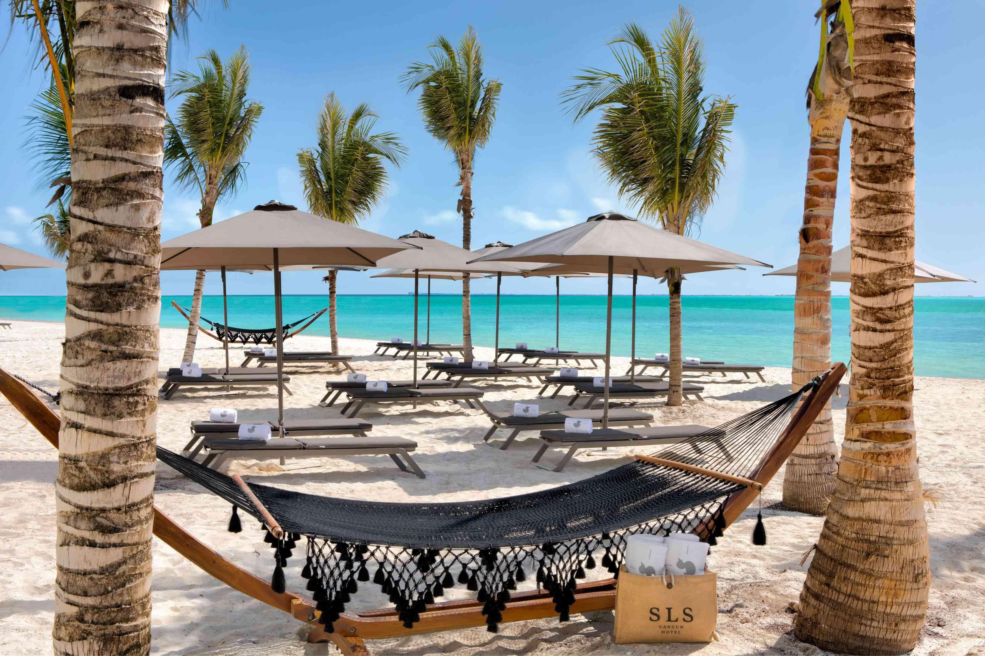 Sitting area on the beach with hammocks and umbrella covered chaise loungers