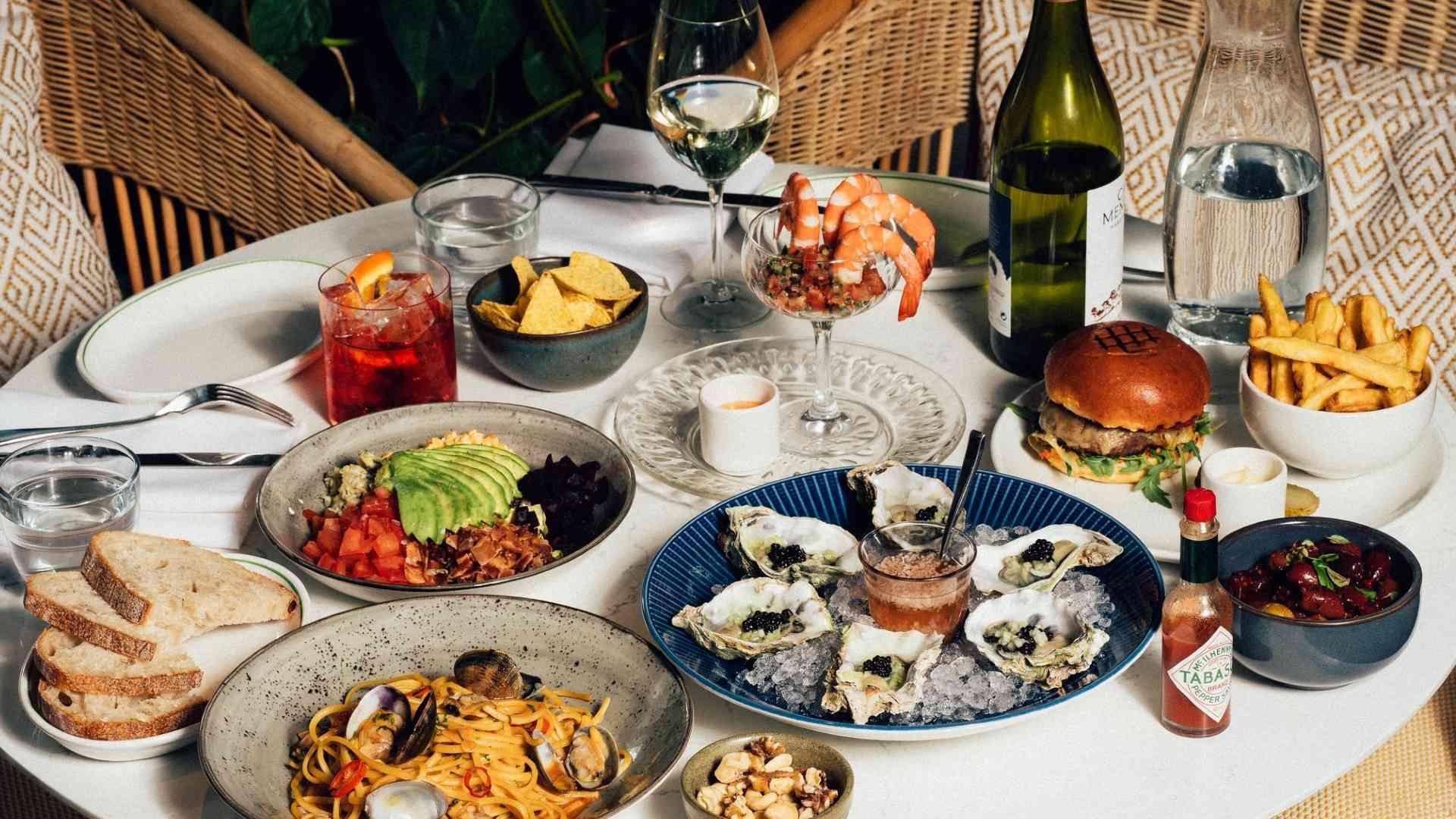 A table set with oysters, pasta, and other delicious food