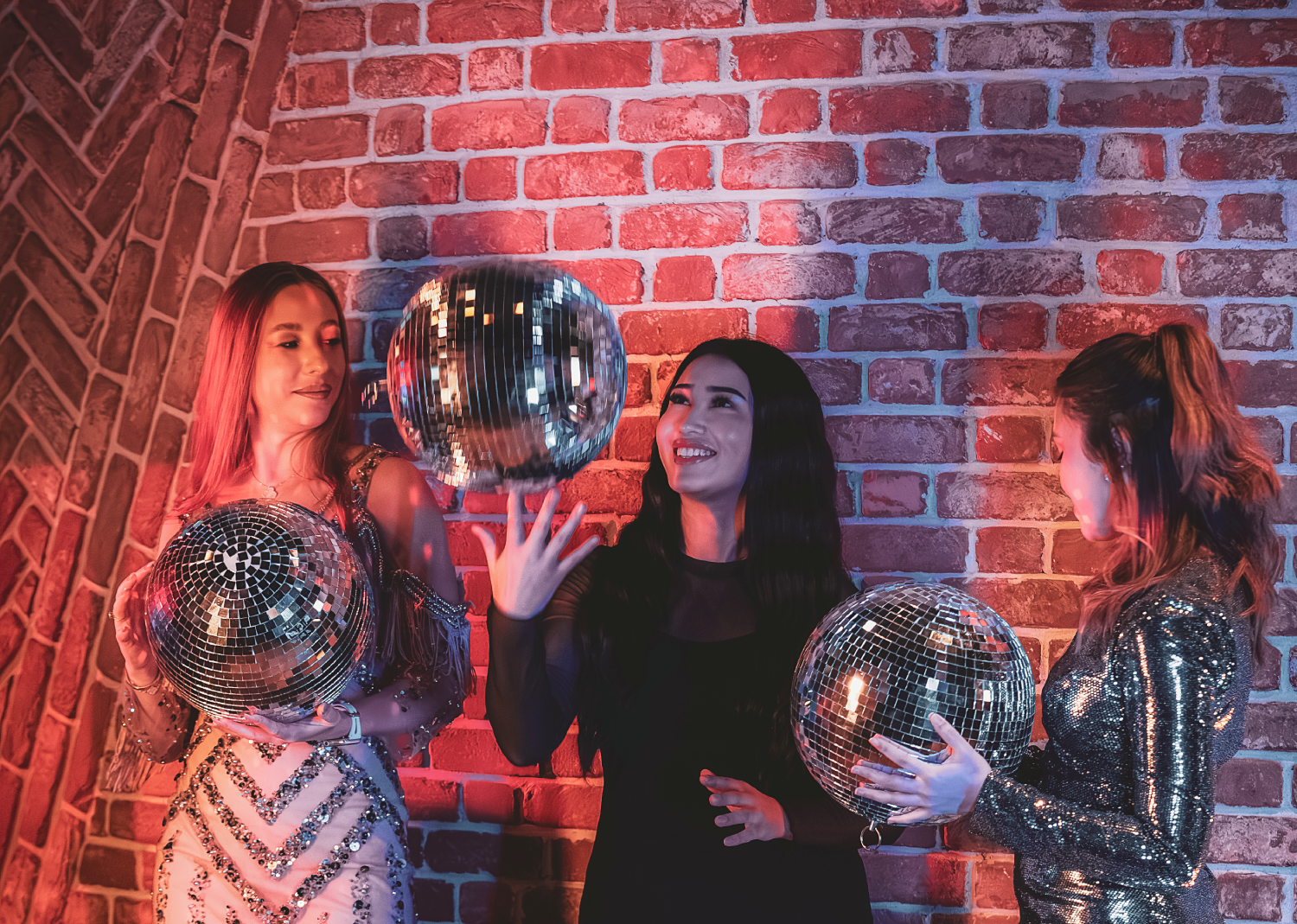 Three women each holding a disco ball 