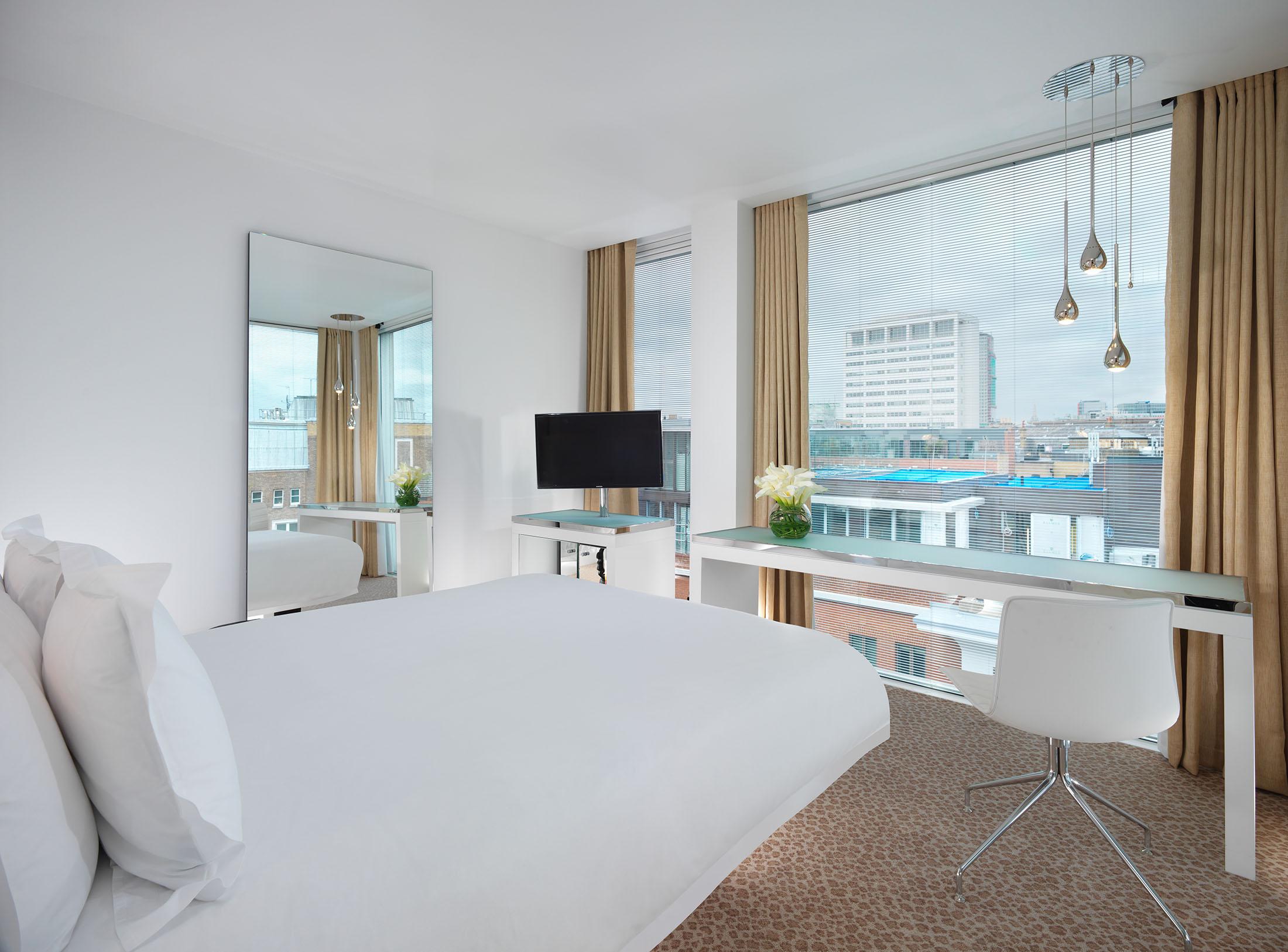 hotel room with bed and desk overlooking the city