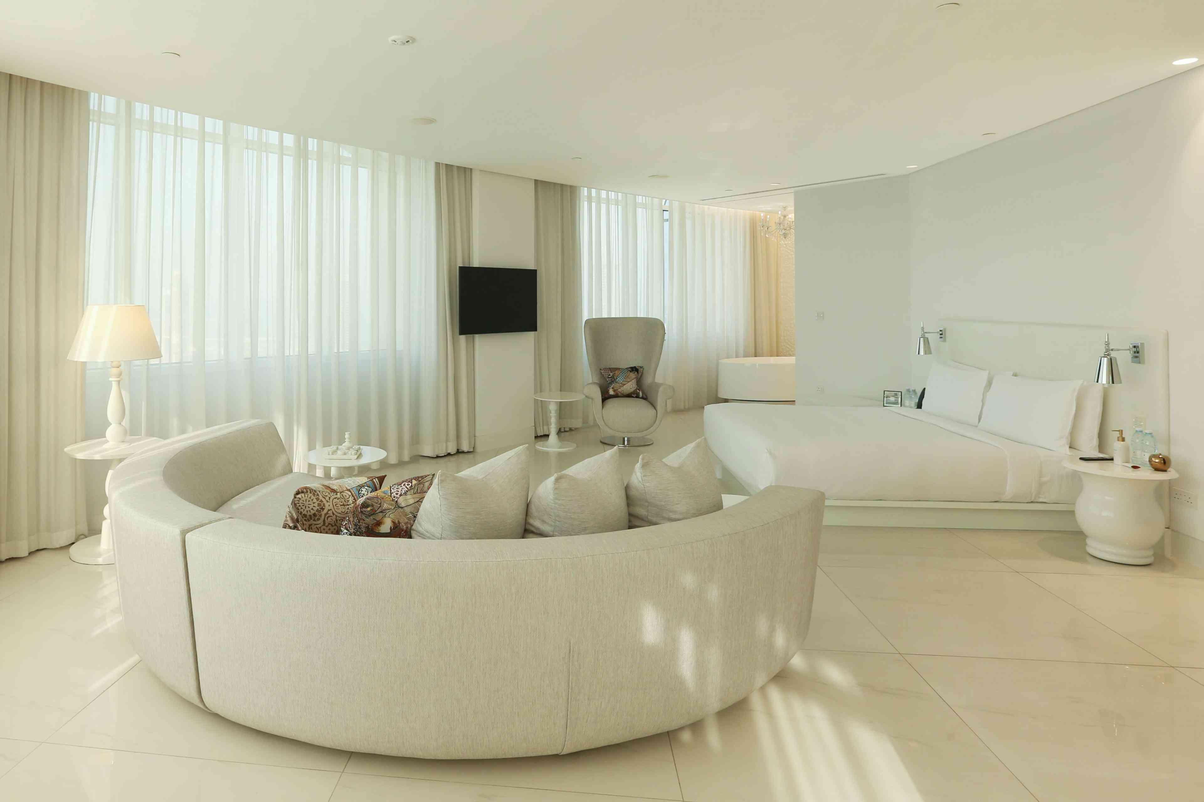 Room with circular white couch and a bed 