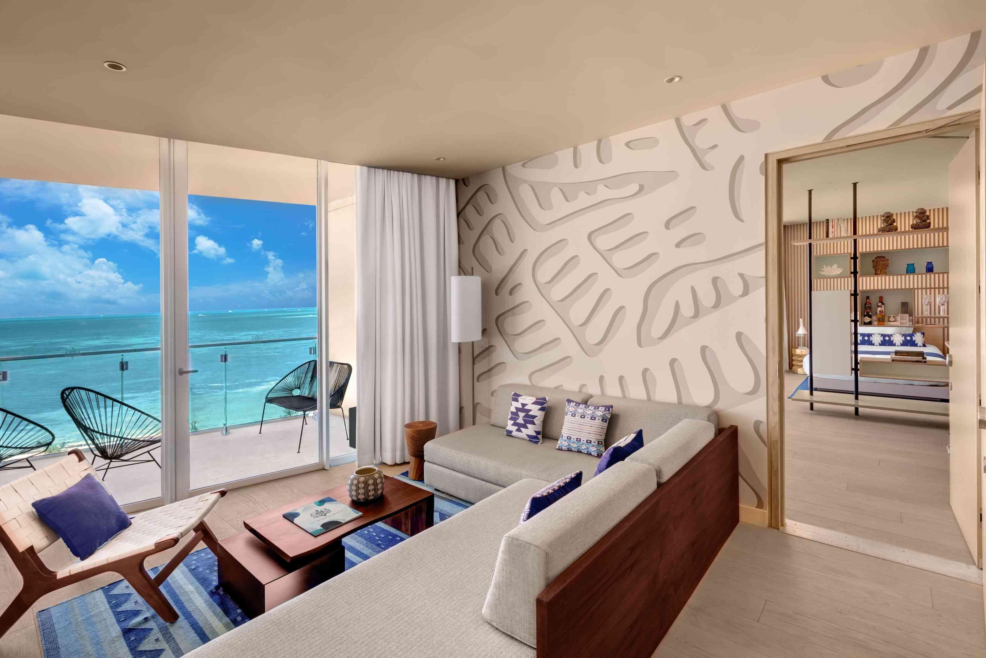 View of living room with an open door leading to the deluxe ocean front one bedroom king suite