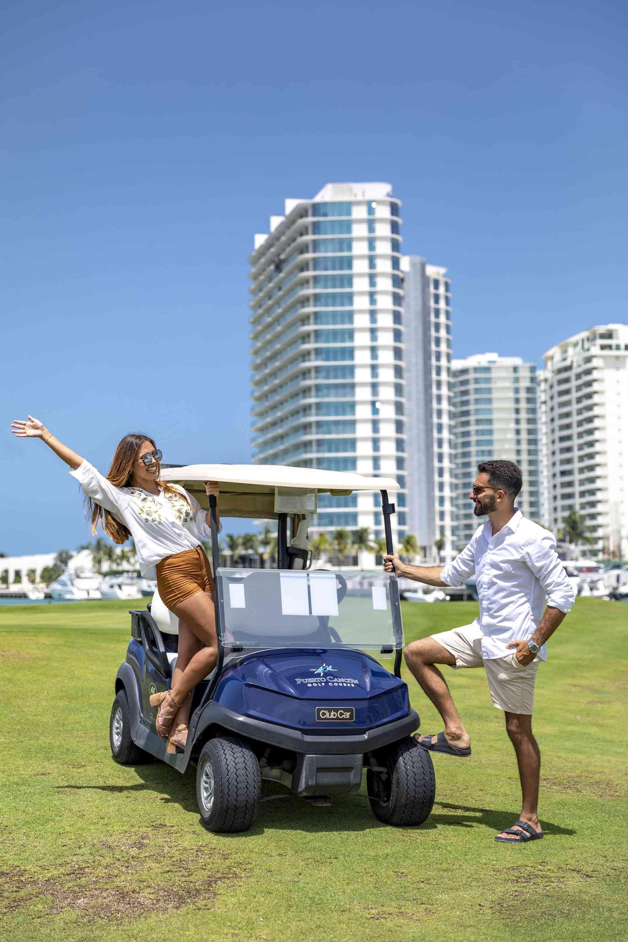 A man and a woman posing on a golf cart