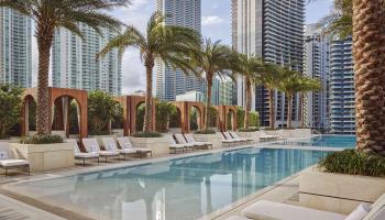 pool surrounded by white lounge chairs and palm trees