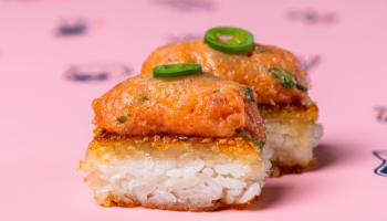 sushi with jalapenos on top sitting on pink packaging