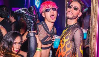 people posing for a photo in a club, holding a blue cocktail