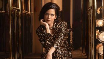 woman dressed up with elbow on knee and palm holding chin up